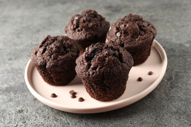 Photo of Delicious chocolate muffins on grey textured table