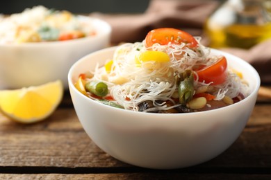 Tasty cooked rice noodles with vegetables on wooden table