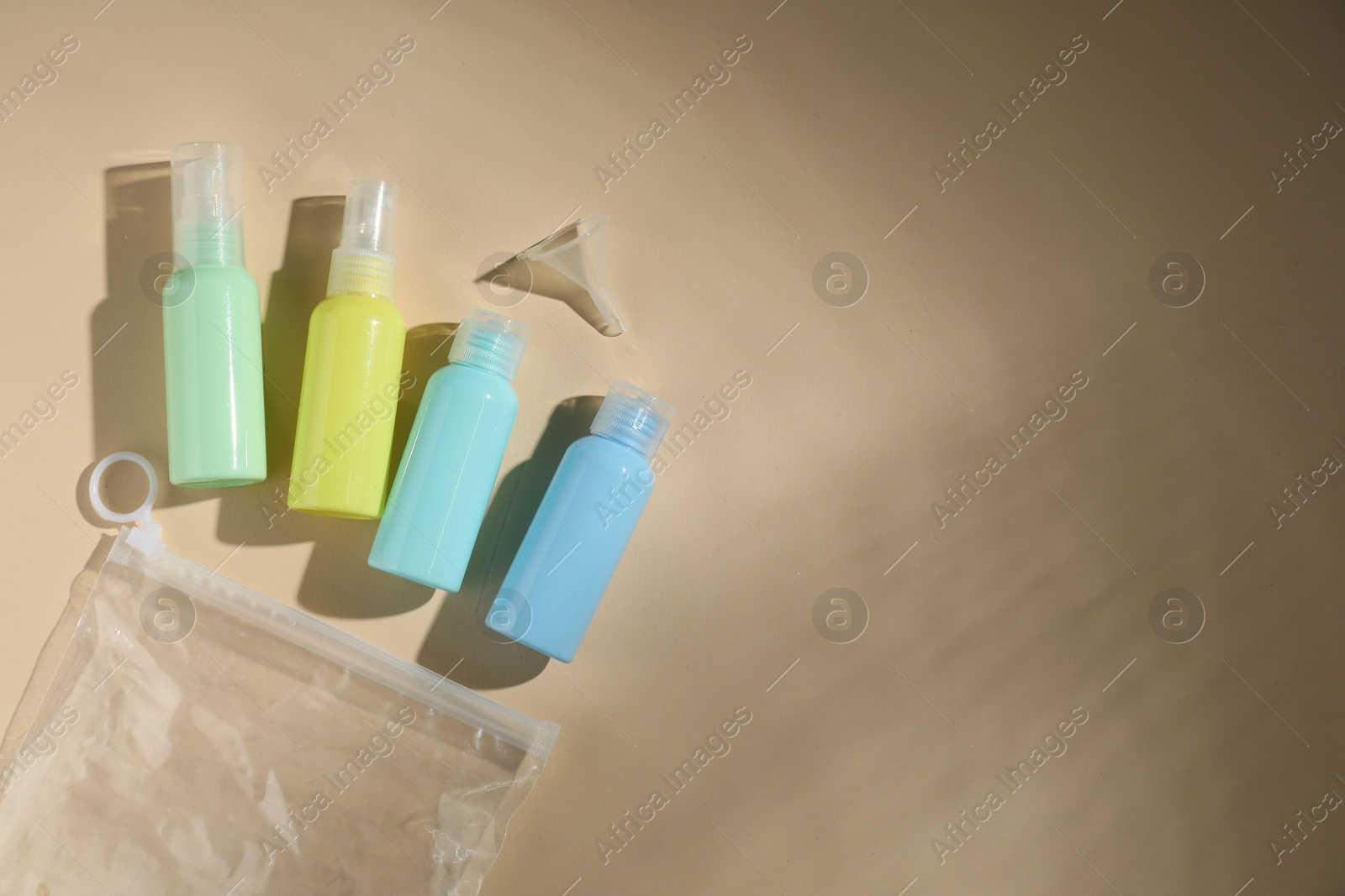 Photo of Cosmetic travel kit and plastic bag on beige background, flat lay with space for text. Bath accessories