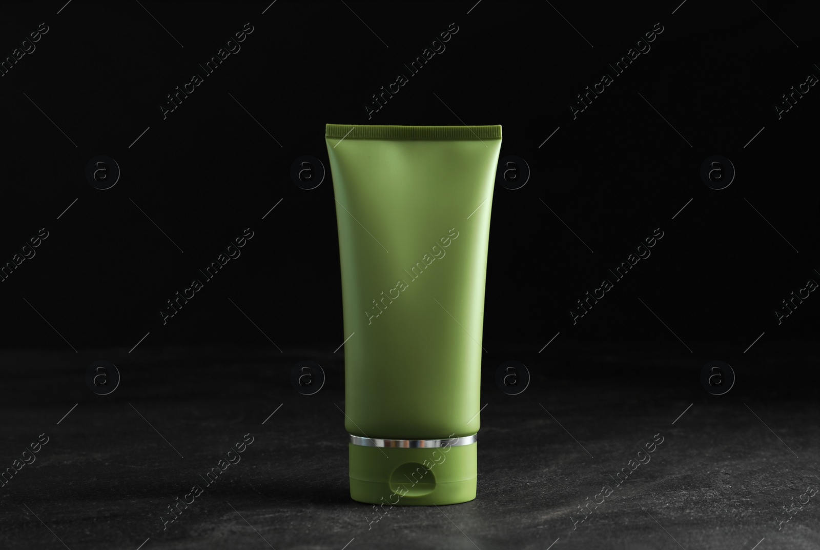 Photo of Tube of cosmetic product on grey stone table against black background