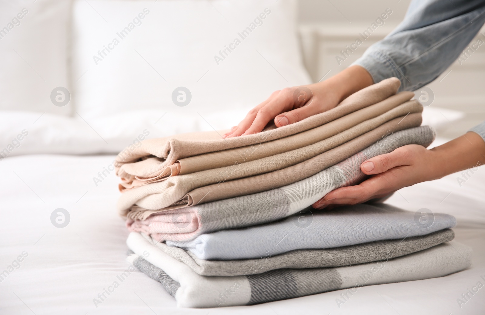 Photo of Woman with folded cashmere clothes on bed, closeup