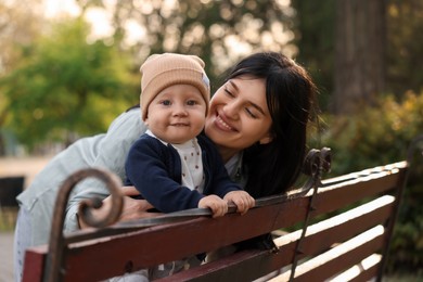 Happy mother and her baby on bench in park