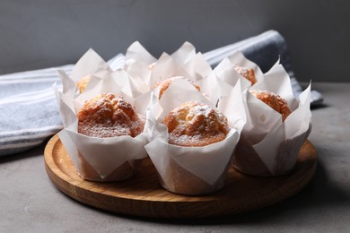 Photo of Delicious muffins with powdered sugar on grey table