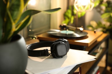 Photo of Stylish turntable with vinyl record indoors, focus on headphones