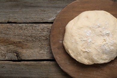 Photo of Fresh yeast dough with flour on wooden table, top view. Space for text