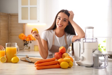 Photo of Young woman making tasty fresh juice at table in kitchen