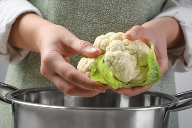Photo of Woman separating fresh cauliflower cabbage above colander, closeup