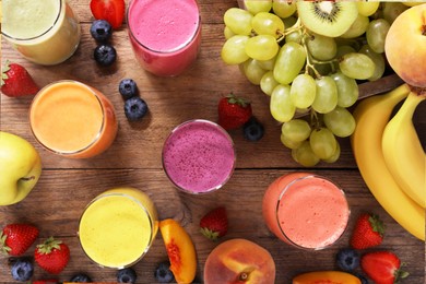 Photo of Many different tasty smoothies and ingredients on brown wooden table, flat lay
