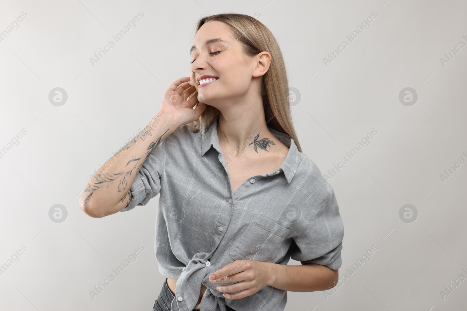 Photo of Portrait of beautiful tattooed woman on light background