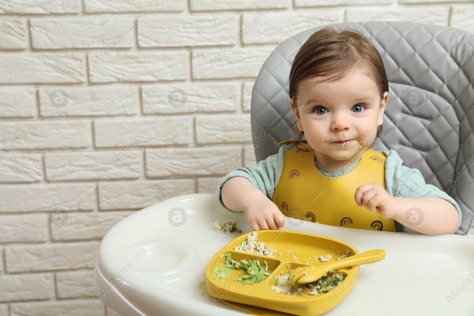 Photo of Cute little baby eating healthy food in high chair indoors. Space for text