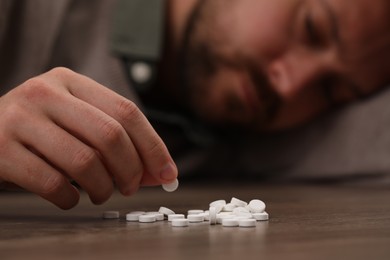 Man with antidepressant pills at table, selective focus