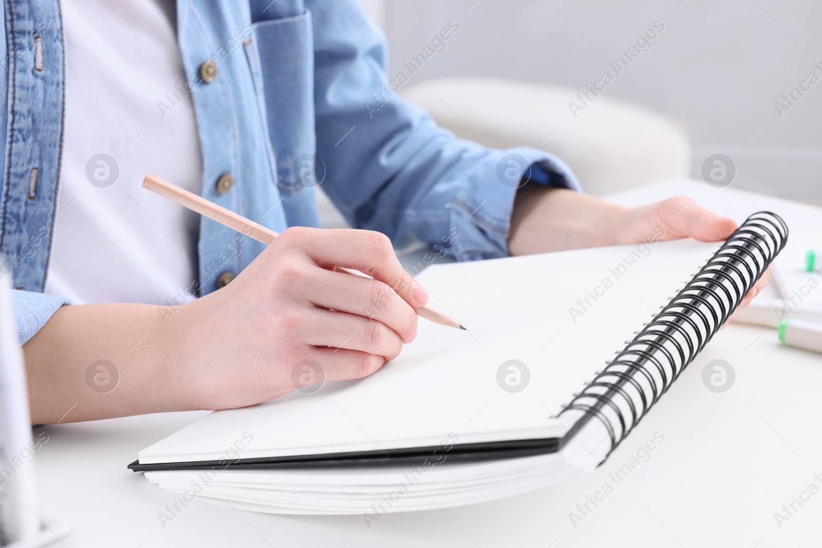 Photo of Young woman drawing in sketchbook indoors, closeup