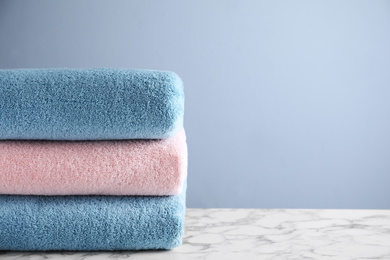Photo of Stack of clean bath towels on white marble table. Space for text