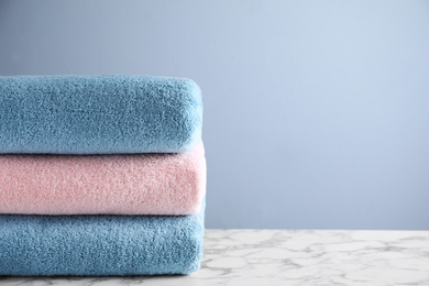 Stack of clean bath towels on white marble table. Space for text