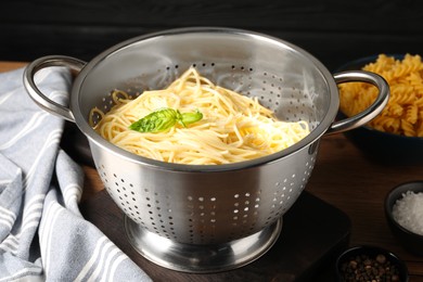 Cooked pasta in metal colander and spices on table, closeup