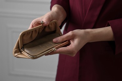 Woman with empty wallet near white wall, closeup