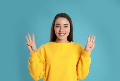 Photo of Woman showing number six with her hands on light blue background