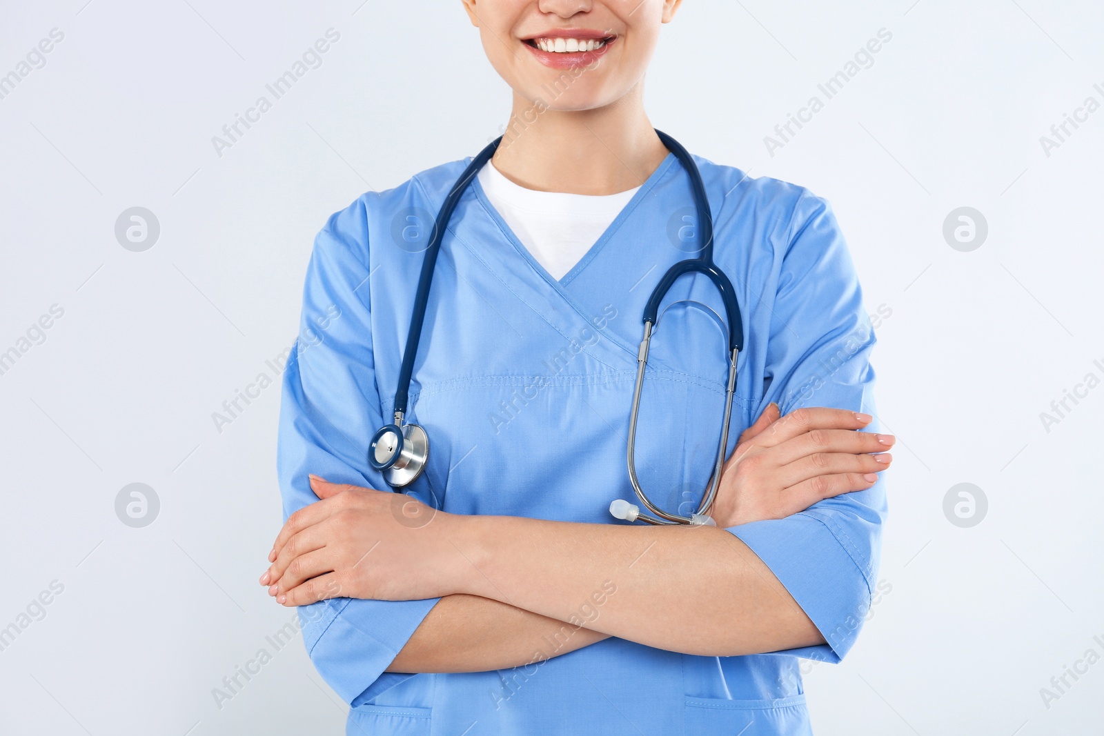 Photo of Young doctor with stethoscope on light background, closeup