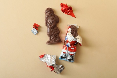 Flat lay composition with chocolate Santa Claus candies on beige background