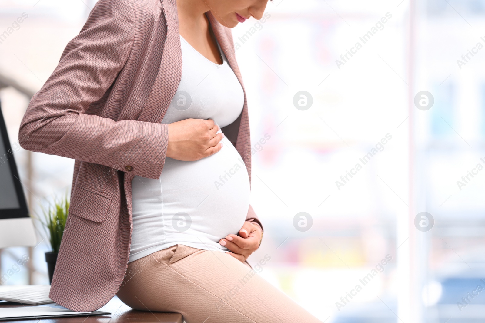 Photo of Young pregnant woman in suit at workplace, closeup. Space for text