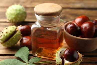 Photo of Chestnuts and jar of essential oil on wooden table