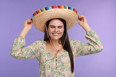 Photo of Young woman in Mexican sombrero hat on violet background