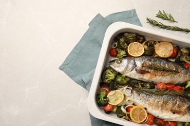 Photo of Delicious fish with vegetables and lemon in baking dish on light marble table, top view. Space for text