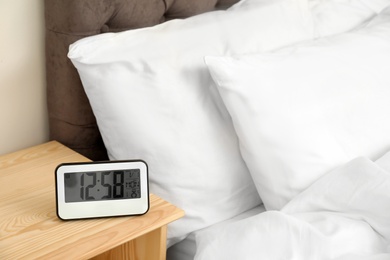 Photo of Digital alarm clock on table in bedroom. Time of day