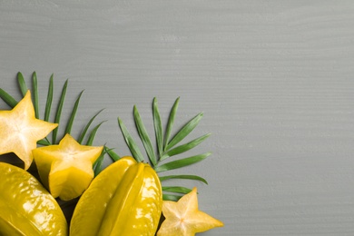 Photo of Delicious carambola fruits on grey wooden table, flat lay. Space for text