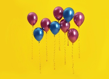 Bright balloons with ribbons on color background