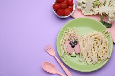 Photo of Creative serving for kids. Plate with cute dog made of tasty pasta, sausage and cucumber on violet table, flat lay. Space for text