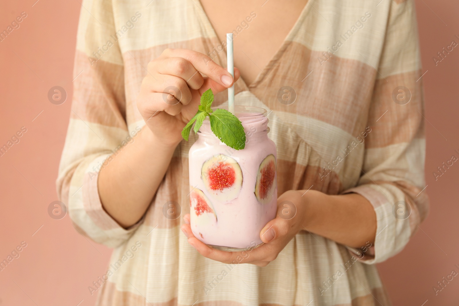 Photo of Woman holding mason jar with fig smoothie on pink background, closeup