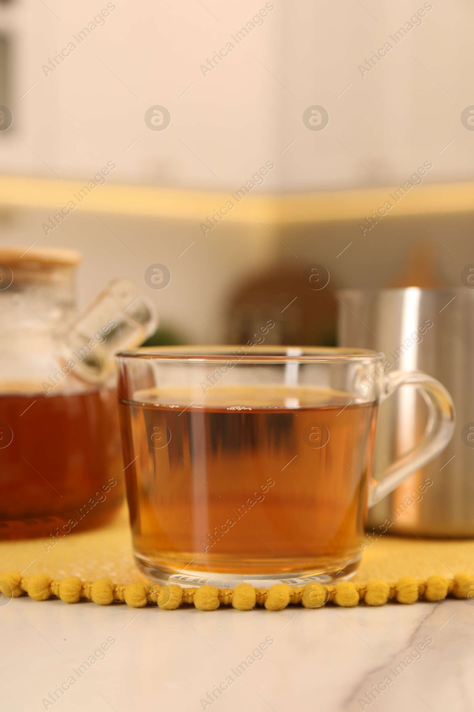 Photo of Aromatic tea in glass cup on light marble table