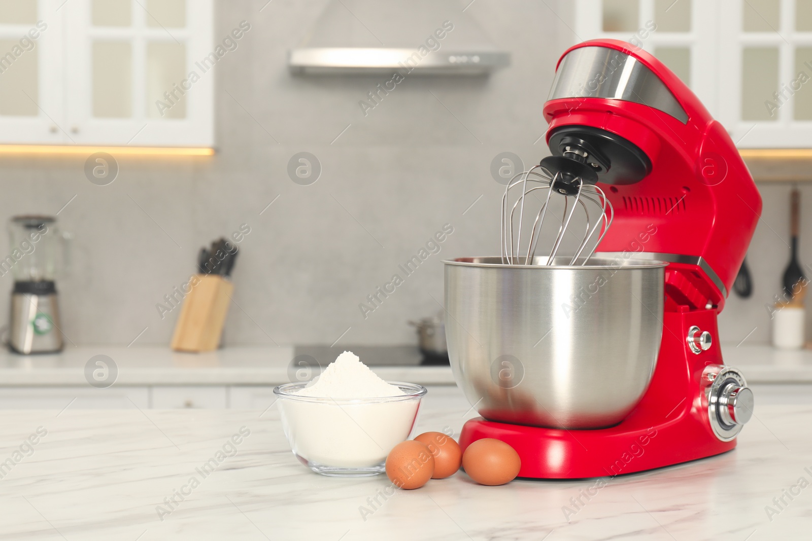 Photo of Modern red stand mixer, eggs and bowl with flour on white marble table in kitchen, space for text