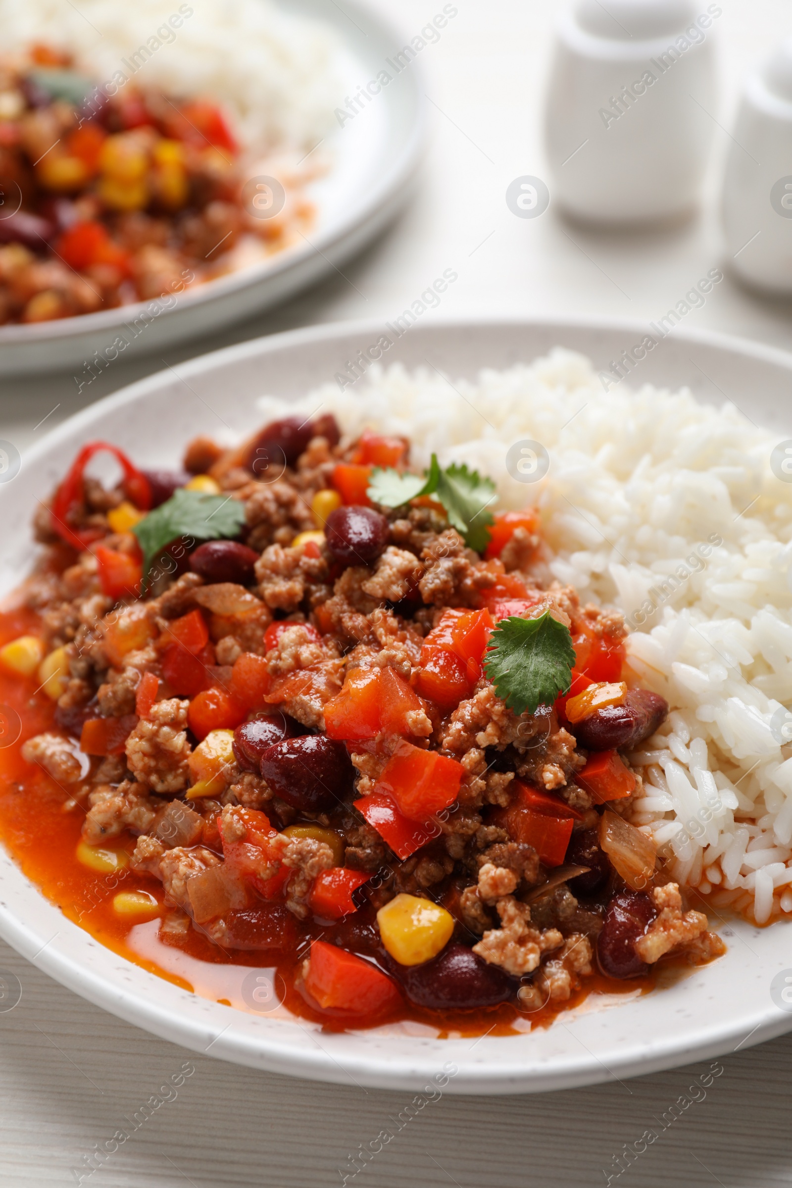 Photo of Plate of rice with chili con carne on white wooden table