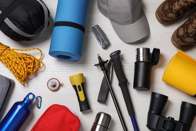 Photo of Flat lay composition with trekking poles and other hiking equipment on white wooden background