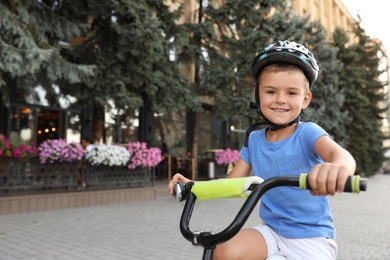 Photo of Happy little boy in helmet riding bicycle on street