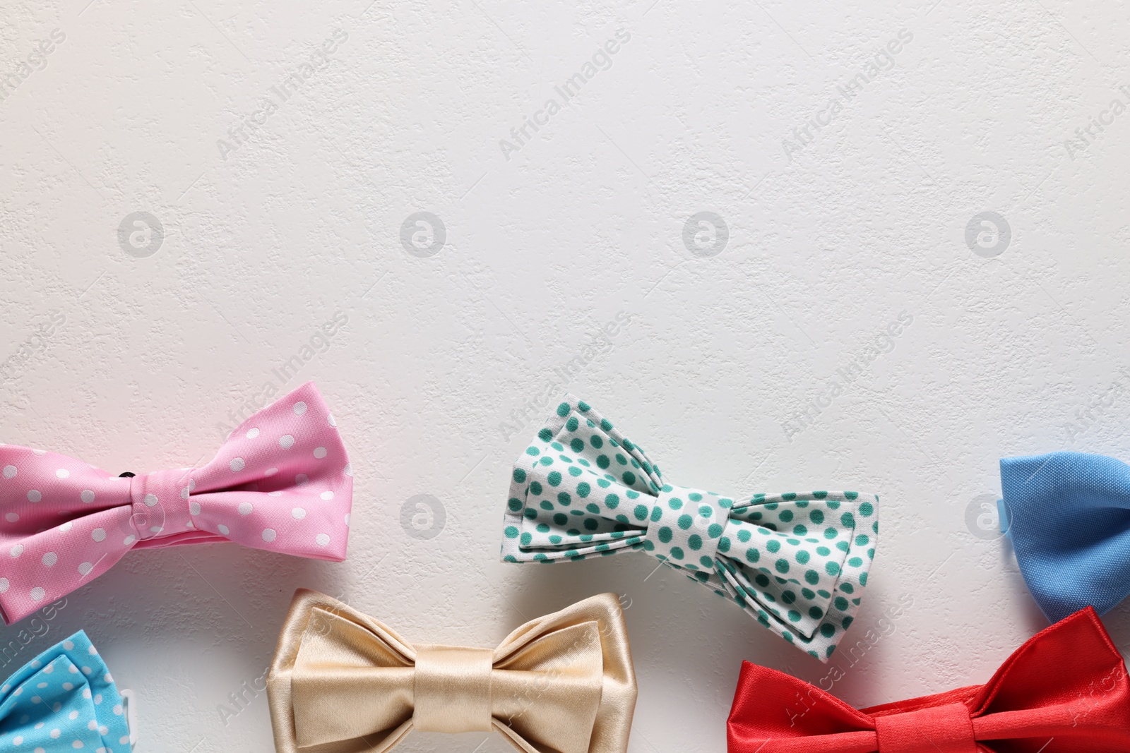 Photo of Stylish color bow ties on white background, flat lay. Space for text