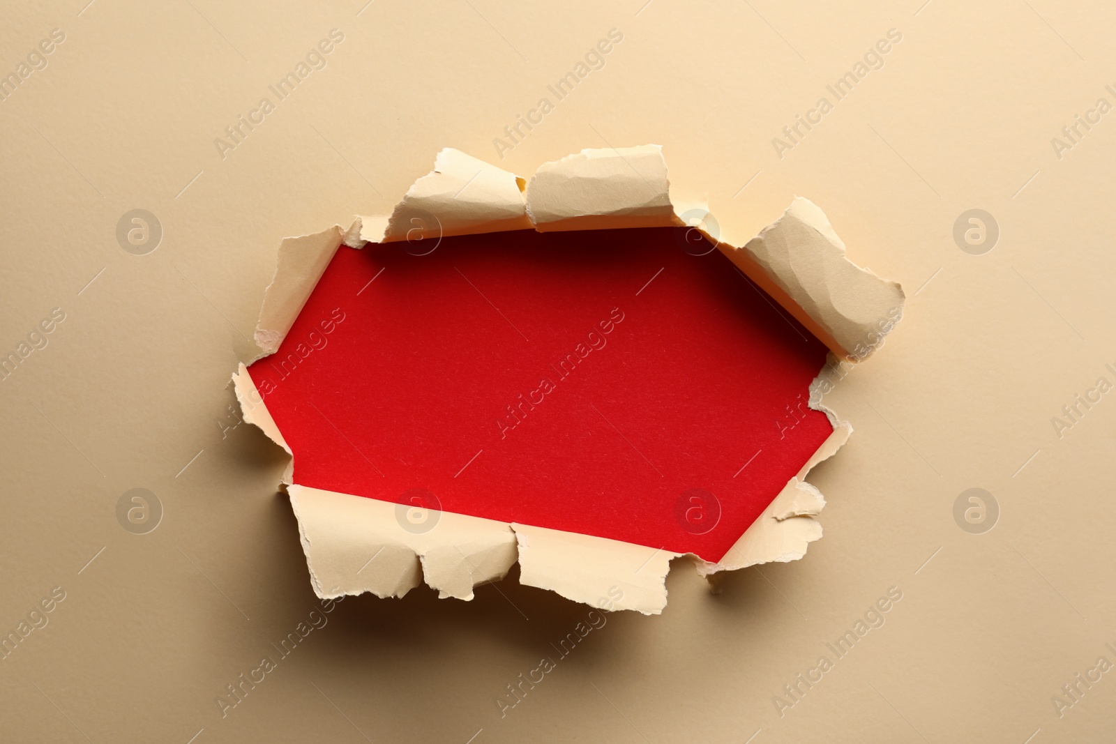 Photo of Hole in light beige paper on red background