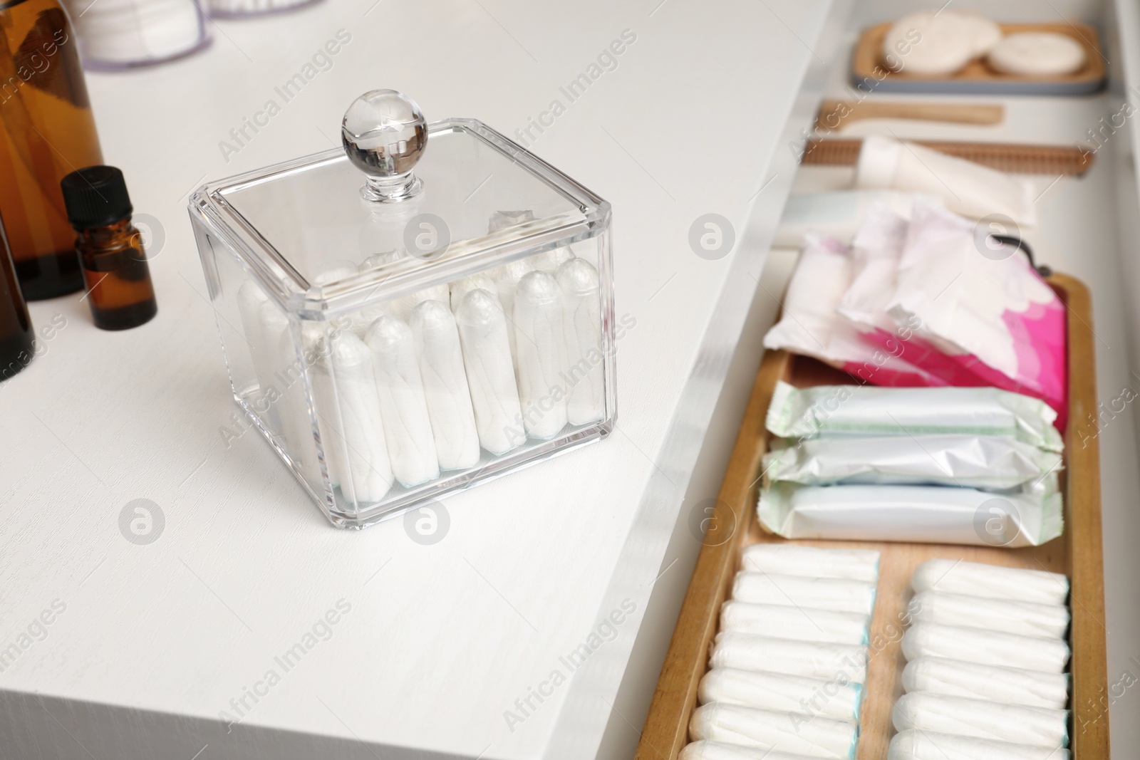 Photo of Many different feminine hygiene products on white chest of drawers