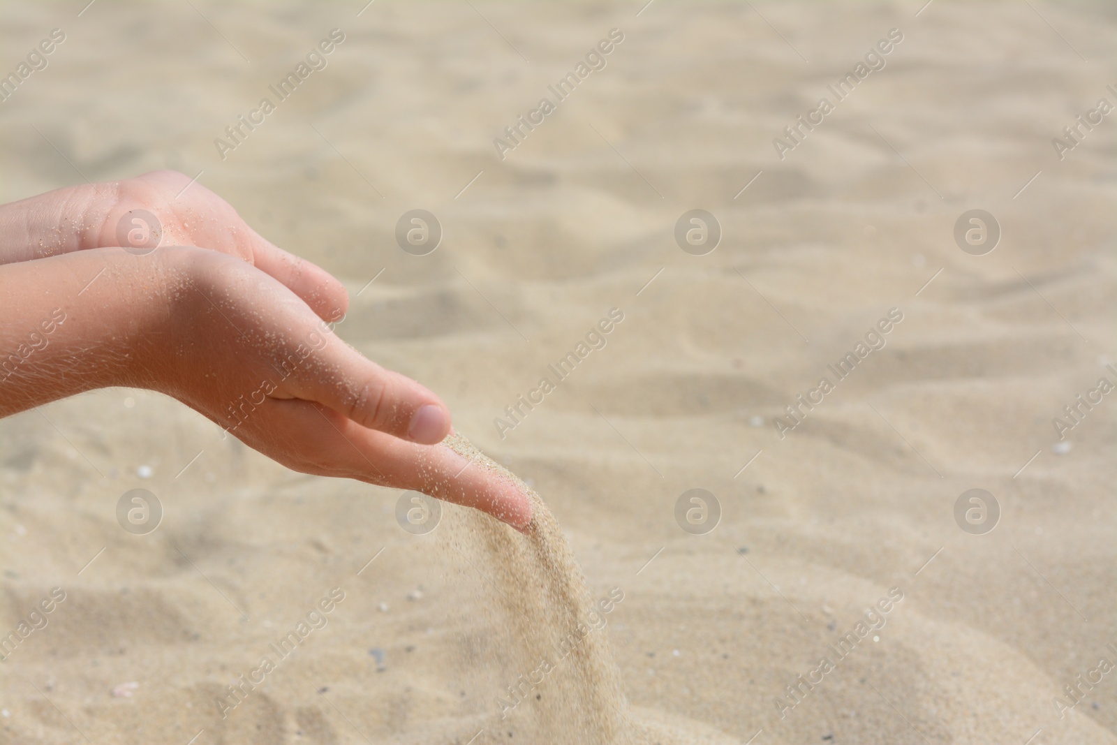 Photo of Child pouring sand from hands on beach, closeup with space for text. Fleeting time concept