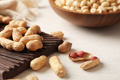 Raw peanuts in shell and board on table