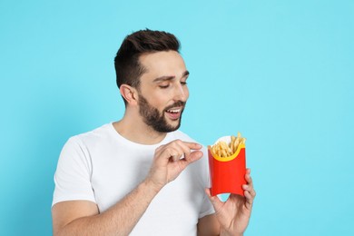Photo of Man with French fries on light blue background