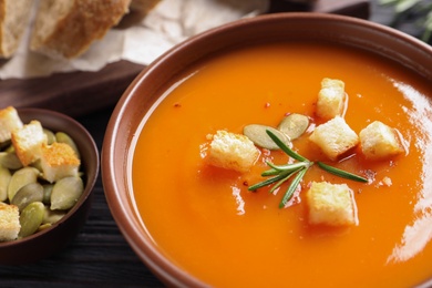 Photo of Bowl of tasty sweet potato soup served on table, closeup