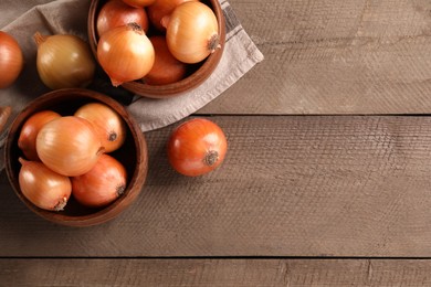 Photo of Many ripe onions on wooden table, flat lay. Space for text
