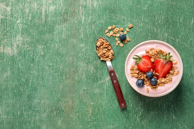 Photo of Bowl with yogurt, berries and granola on wooden background, top view