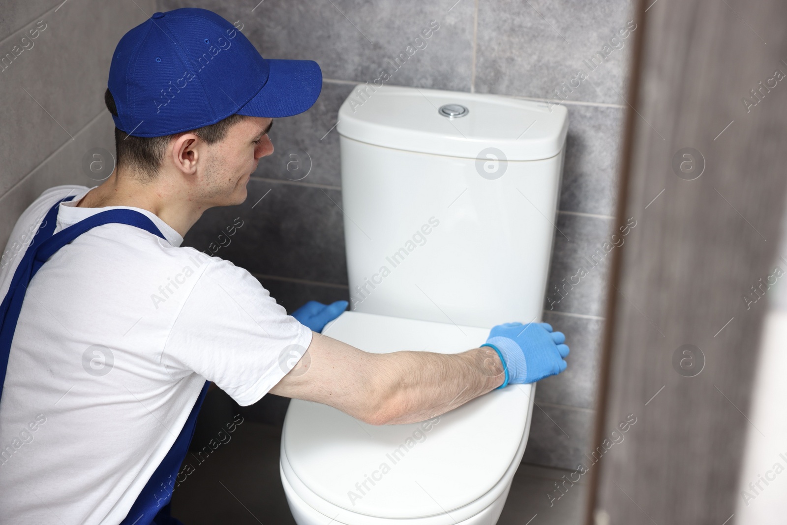 Photo of Plumber wearing protective gloves repairing toilet bowl in water closet