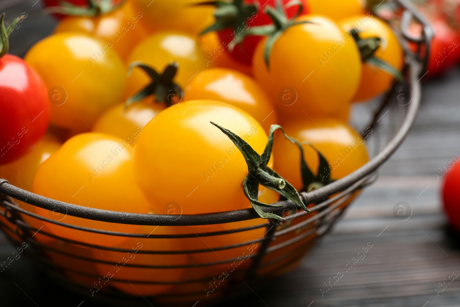 Photo of Ripe red and yellow tomatoes in metal basket on table, closeup