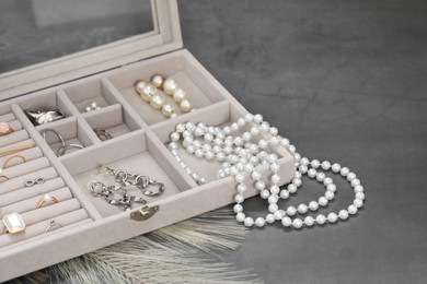 Photo of Jewelry box with many different accessories on grey table, closeup