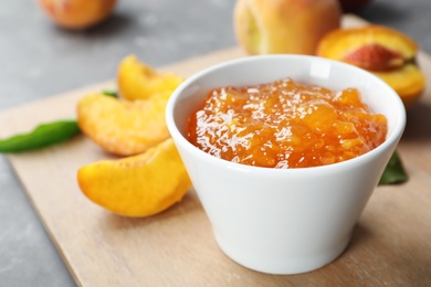 Photo of Bowl with tasty peach jam on table